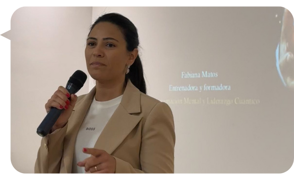 Fabiana Matos hablando en una conferencia sobre reprogramación mental y liderazgo cuántico, con micrófono en mano.