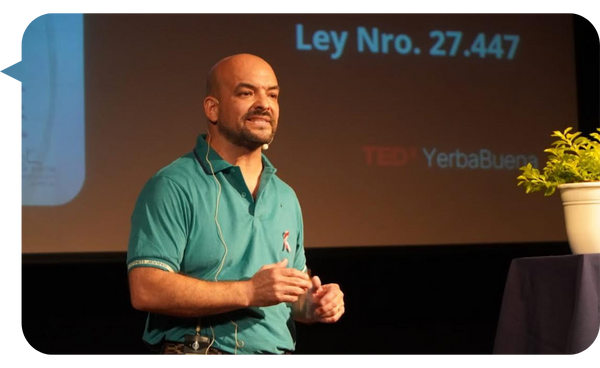 Hugo Quintana dando una charla en un evento TEDx Yerba Buena, vistiendo una camiseta verde y utilizando un micrófono de diadema.